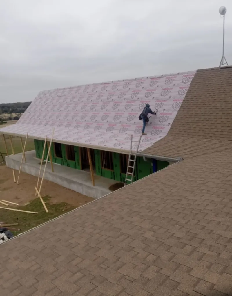 Worker preparing underlayment for a metal roof installation in Cambridge